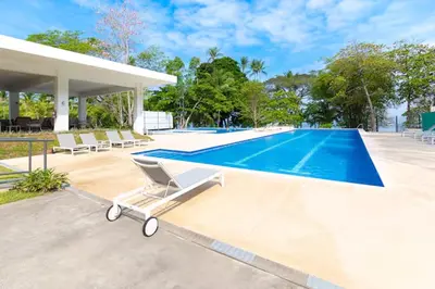 a swimming pool in a villa with a lounge chair next to a pool at Playa Mantas - 7th Floor - Sea View - Beach Club Access - Balcony - Beach in Punta Leona