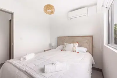 a white bedroom with a white bed with two pillows at Playa Mantas - 7th Floor - Sea View - Beach Club Access - Balcony - Beach in Punta Leona