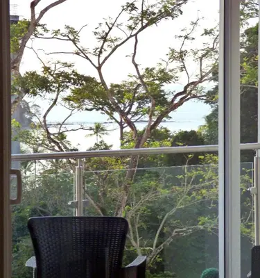 a window with a chair in front of a tree at Playa Mantas - 7th Floor - Sea View - Beach Club Access - Balcony - Beach in Punta Leona