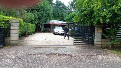 a man walking through a gate in a parking lot at Casa Tica in Playa Flamingo
