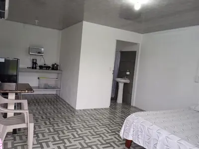 a bedroom with a bed and a desk and a kitchen at La Loma Lodge in Aguas Zarcas