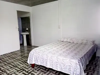 a white bedroom with a bed and a bathroom at La Loma Lodge in Aguas Zarcas