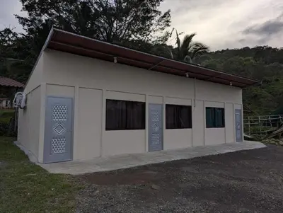 a small white building with two doors and windows at La Loma Lodge in Aguas Zarcas