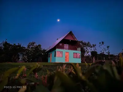 a house in a field with the moon in the sky at Cinnamon Lodge in Upala