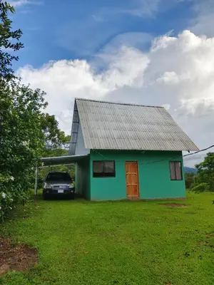 a green house with a car parked in front of it at Cinnamon Lodge in Upala