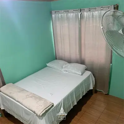 a small bed in a room with a fan at Cinnamon Lodge in Upala