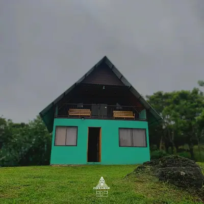 a green house with a black roof on a field at Cinnamon Lodge in Upala