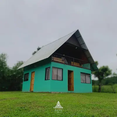 a green house with a black roof on a field at Cinnamon Lodge in Upala