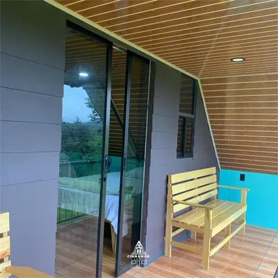 a wooden bench on the porch of a house at Cinnamon Lodge in Upala