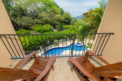 a balcony with two chairs and a swimming pool at Bella Vista 8B 3 bedr 3 1 and half bath in Jacó
