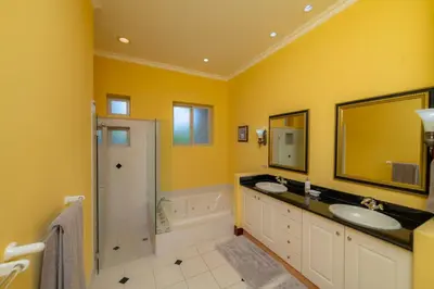 a yellow bathroom with two sinks and a shower at Bella Vista 8B 3 bedr 3 1 and half bath in Jacó