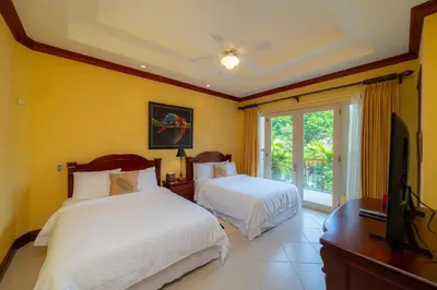 a bedroom with two beds and a flat screen tv at Bella Vista 8B 3 bedr 3 1 and half bath in Jacó