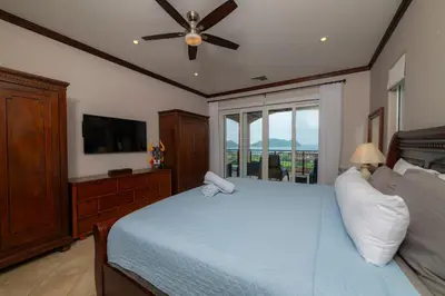a bedroom with a blue bed with a ceiling fan at Altavista 4C 3 bdr 3 bath Ocean View in La Mona