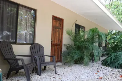 two chairs and a table in front of a house at Playa Negra Surf Lodge in Playa Negra