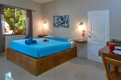 a bedroom with a bed with blue sheets and a table at Playa Negra Surf Lodge in Playa Negra