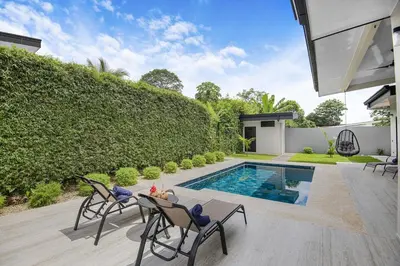 a backyard with a pool and a table and chairs at Brand New Villa! - Just 10 Mins Walk To The Beach in Uvita