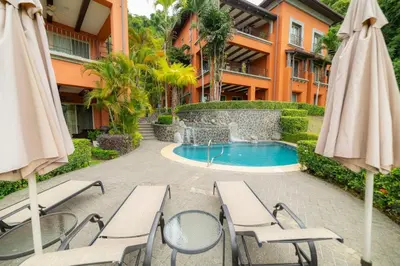 a resort with a swimming pool and chairs and umbrellas at Montebello 4E 3bed 3 bath in Jacó