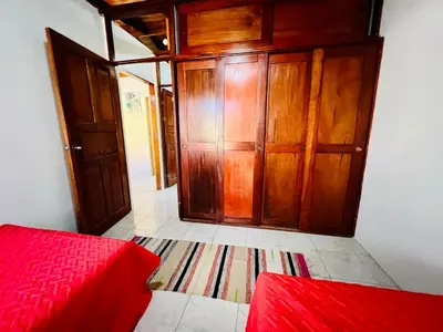 a bedroom with a red bed and wooden cabinets at El Papagayo Verde 5 min walk to the beach and downtown in Coco