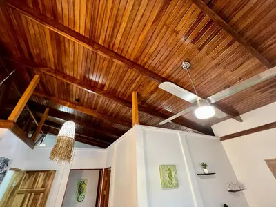 a ceiling fan in a room with wooden ceilings at El Papagayo Verde 5 min walk to the beach and downtown in Coco
