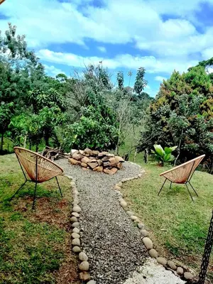 two benches sitting in the grass near a fire pit at Modern Villa Exclusive Tropical Nature Retreat Rio Celeste 6 to 8 Guests in Upala