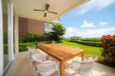 a patio with a wooden table and white chairs at Montecielo 3E - 3 bdr 3 1 and a half bath Ocean View in La Mona