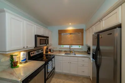 a kitchen with white cabinets and a stainless steel refrigerator at Veranda 3B - 2 Bedr 2 Bath in La Mona