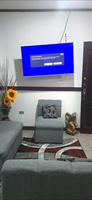 a living room with a couch and a tv on a wall at Apartamentos Adela cerca embajada americana in San José