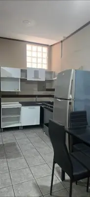 a kitchen with a refrigerator and a table with a chair at Apartamentos Adela cerca embajada americana in San José