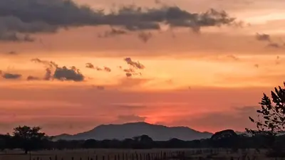 a sunset over a field with a mountain in the background at Hotel El Paraje in Santa Cruz