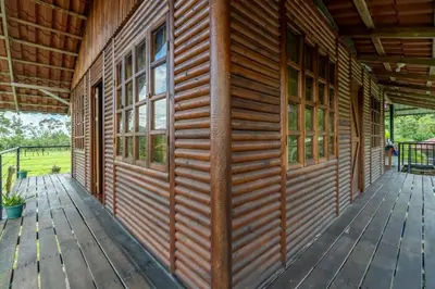 a wooden wall of a cabin with windows on a porch at Cabañas Retiro Del Rio in Guayabal