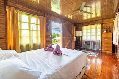 a bedroom with a bed with pink slippers on it at Cabañas Retiro Del Rio in Guayabal