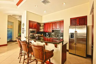 a kitchen with wooden cabinets and a bar with bar stools at Bella Vista 4B - 3 bdr -3 1 and a half bath Ocean View in La Mona