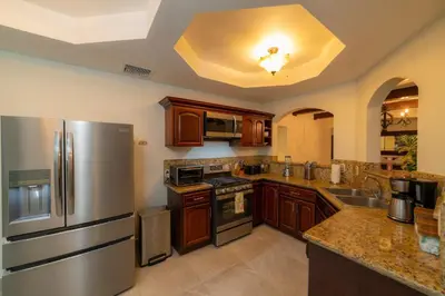 a kitchen with wooden cabinets and a stainless steel refrigerator at Casa Patron 6 bdr Private pool in La Mona