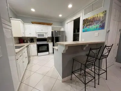 a kitchen with white cabinets and a counter with stools at Sweet fishing apartment in Isla Herradura