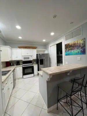 a kitchen with white cabinets and a counter with stools at Sweet fishing apartment in Isla Herradura