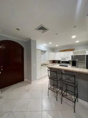 a kitchen with white cabinets and a counter with two chairs at Sweet fishing apartment in Isla Herradura