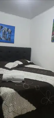 a bed with a black and white blanket on it at Rohrmoser a 100 metros de la embajada americana in San José