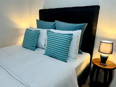 a bed with blue and white pillows and a lamp at Alto Cruz Executive Loft in Turrialba