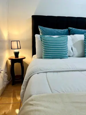 a bed with blue and white pillows and a lamp at Alto Cruz Executive Loft in Turrialba