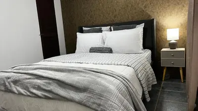 a bedroom with a large bed with white pillows at Executive Apartment Escazú in Escazu