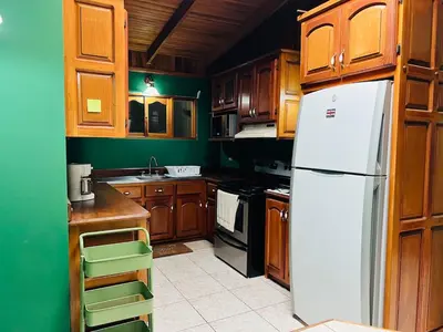 a kitchen with a white refrigerator and wooden cabinets at Family Nest Turrialba in Turrialba
