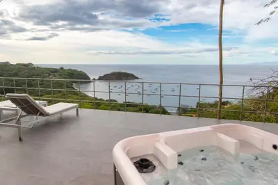 a bath tub on a balcony with a view of the ocean at A Slice of Paradise in Sardinal