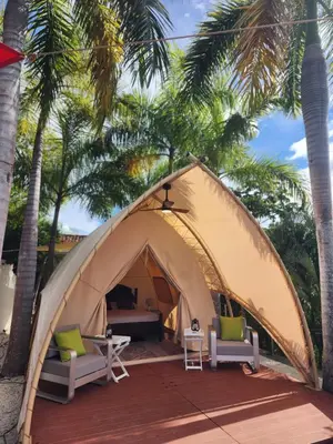 a tent with two chairs and a table in front of palm trees at A Slice of Paradise in Sardinal