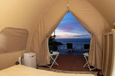 a bedroom with a tent with a view of the ocean at A Slice of Paradise in Sardinal