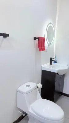 a white bathroom with a toilet and a sink at Casa Colibrí Playa Blanca in Paquera