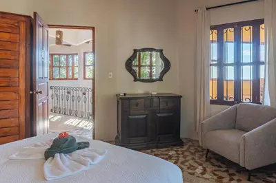 a room with a bed and a chair and a mirror at Casa Sonora - Ocean View in Carrillo