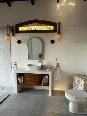 a bathroom with a sink and a mirror and a toilet at Casa Selvática Wildlife-Happiness in Uvita