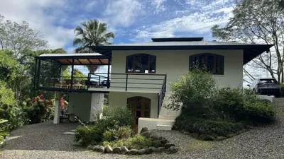 a small white house with a balcony in a yard at Casa Selvática Wildlife-Happiness in Uvita