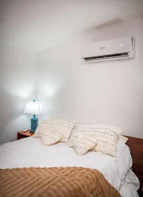 a bed with two pillows on it with a fan at Hotel La Pérgola in Sarapiquí