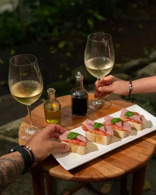two people holding glasses of wine and a plate of food at Hotel La Pérgola in Sarapiquí